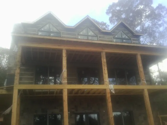 Dormers and porch framing on a large log home under construction — Roof Coating work by our crew in Thomasville