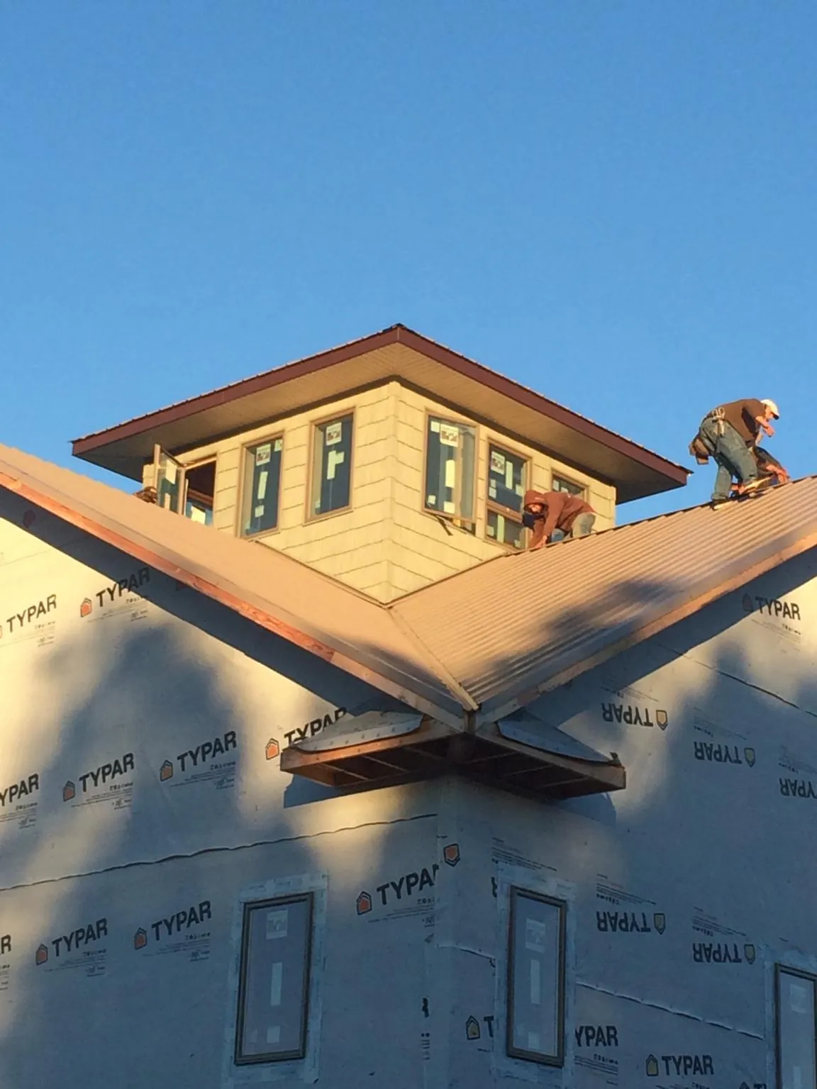 Roofers working around a rooftop cupola on a new metal roof at sunset — Roof Waterproofing in Thomasville by Roofing Brothers
